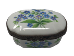 Whimsical Blooms: White Oval Limoges Box with Blue Flower Bouquet